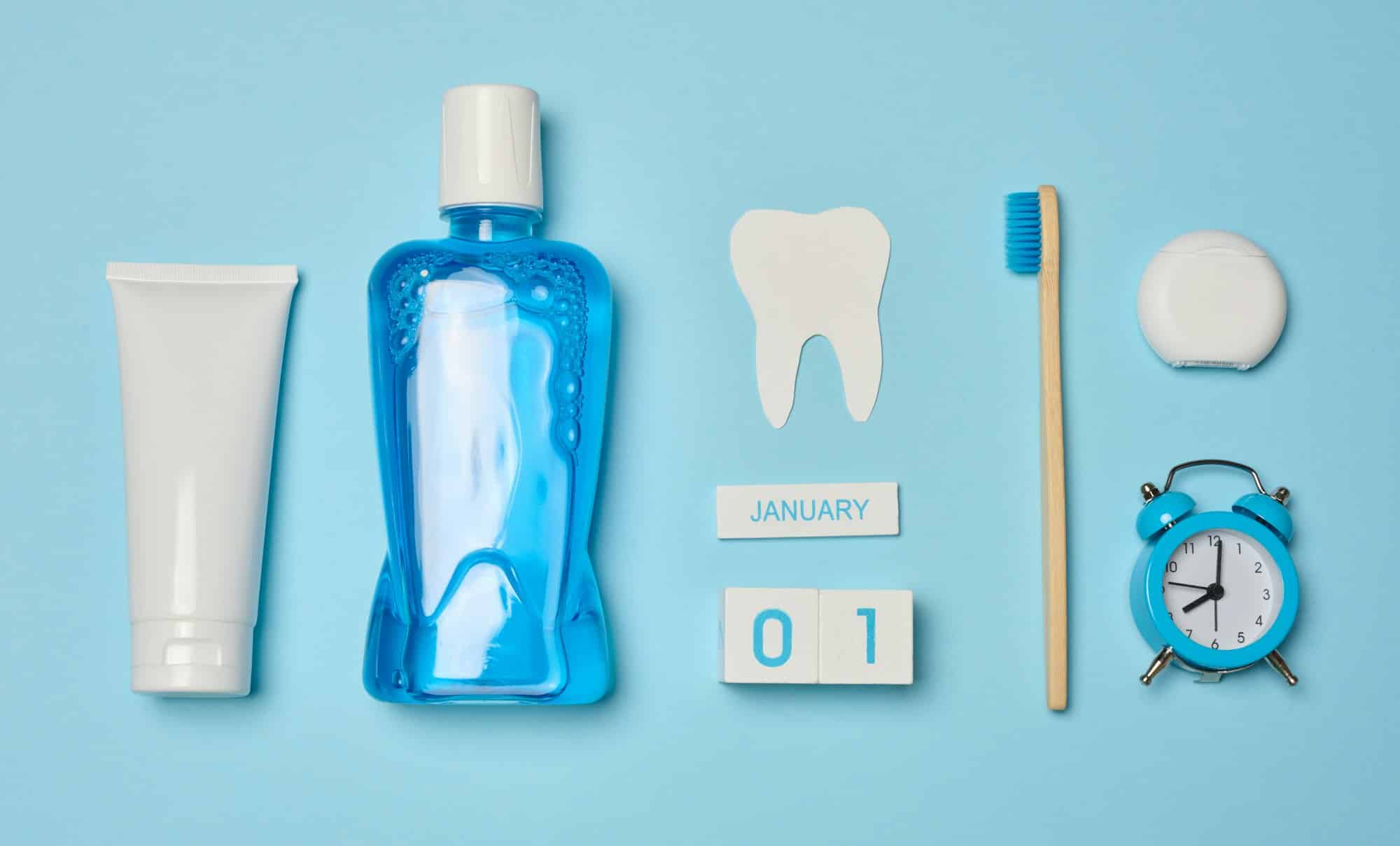 Mouthwash, toothpaste tube, dental floss on a blue background, oral hygiene.