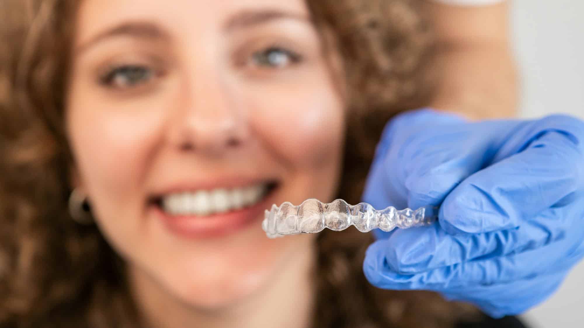 Orthodontic specialist adjusting and placing invisible aligners on woman